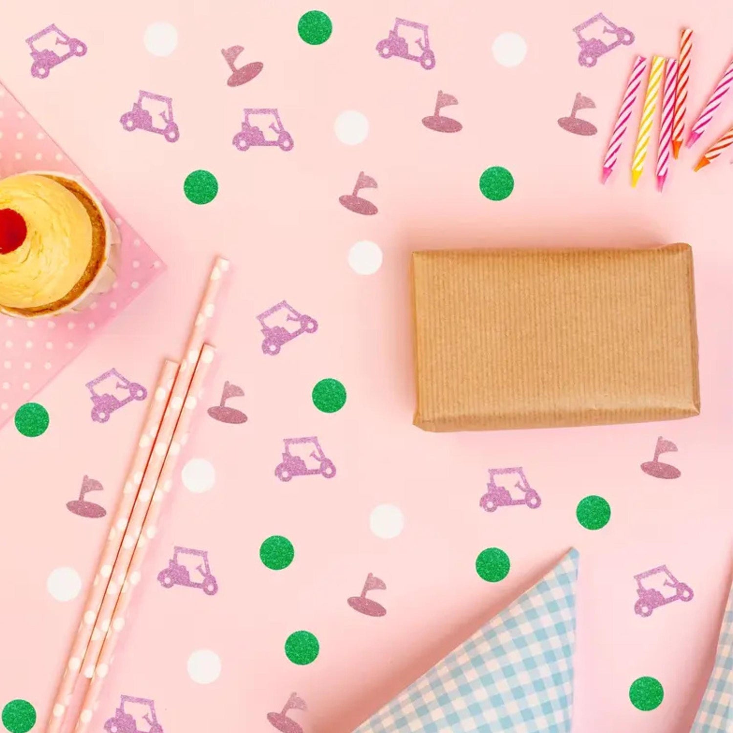 a pink table with a cupcake, candy sticks, and napkins